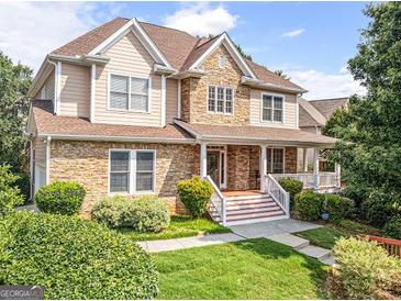 Charming home featuring stone accents, a welcoming front porch, and lush landscaping at 2810 Promenade Pl, Buford, GA 30519