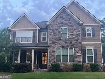 Charming two-story home with stone and wood siding and inviting front porch with chairs at 8340 Nolandwood Ln, Villa Rica, GA 30180
