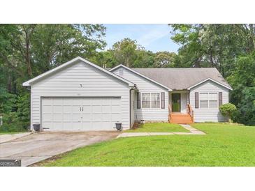 Charming home featuring a two-car garage and a well-maintained lawn, surrounded by mature trees at 160 Country Mill Ln, Stockbridge, GA 30281