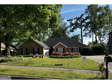 Well-maintained brick home with a lush lawn, mature trees, and vibrant flower beds adding curb appeal at 187 Pine Branch Dr, Stockbridge, GA 30281