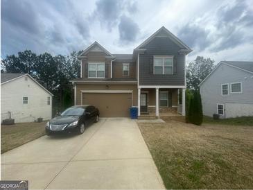 Charming two-story home with a two-car garage, lovely yard, and well-maintained landscaping at 5470 Hilltop Pass, Fairburn, GA 30213