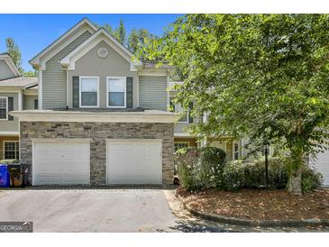Charming townhome featuring a two-car garage with stone accents, mature landscaping, and neutral siding at 508 Las Brasis Ct, Peachtree City, GA 30269