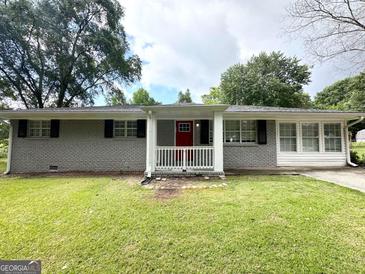 Charming single-story home with a brick facade, a red front door and a well-maintained lawn at 3948 Regent St, Douglasville, GA 30134
