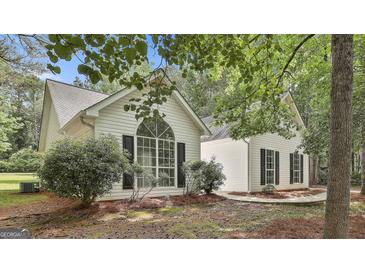 Charming single-Gathering home boasts a striking arched window and black shutters, nestled amongst mature trees at 288 Winthrop Dr, Sharpsburg, GA 30277