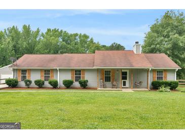 Charming single-story home with a well-maintained lawn, inviting porch with swing, and beautiful green trees at 552 New Hope Rd, Mcdonough, GA 30252