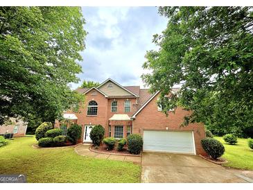 Charming two-story brick home with lush landscaping, a well-manicured lawn, and an attached two-car garage at 759 Hennepin Ter, Mcdonough, GA 30253