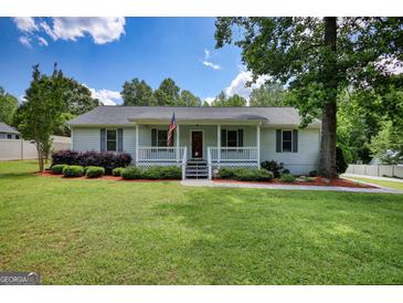 Charming home features a well-manicured lawn, an inviting porch, and delightful landscaping for great curb appeal at 1130 Rawlings Dr, Rutledge, GA 30663