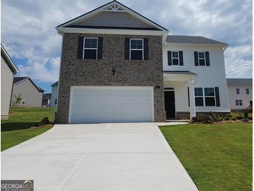 Two-story home boasts brick and siding, a two-car garage, and a well-manicured front yard at 173 Aster Ave, Locust Grove, GA 30248
