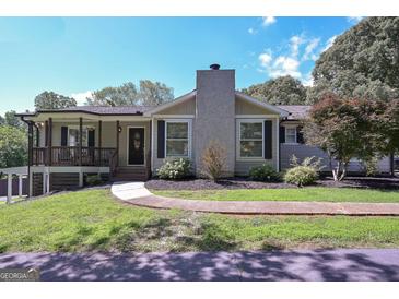 Charming home featuring a stone chimney, inviting front porch, and well-maintained landscaping at 8321 Banks Mill Rd, Douglasville, GA 30135