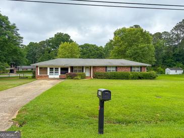Charming brick ranch home features a well-manicured lawn and mature landscaping at 5141 Hiram Lithia Springs Rd, Powder Springs, GA 30127