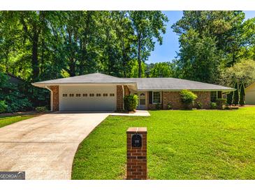 Charming brick ranch home with a well-manicured lawn, a two-car garage and a long driveway at 105 Lake Forest Drive, Peachtree City, GA 30269