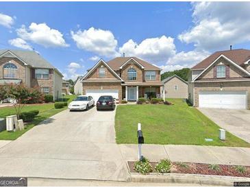 Charming two-story home with a well-maintained lawn and a two-car garage on a sunny day at 718 Florigen Ln, Fairburn, GA 30213