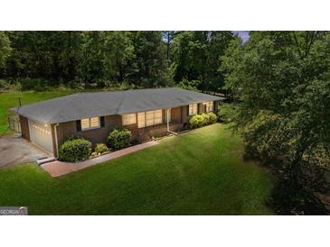 Brick home featuring a lush lawn and mature trees, showcasing its serene setting and classic design at 416 S Carroll Rd, Villa Rica, GA 30180