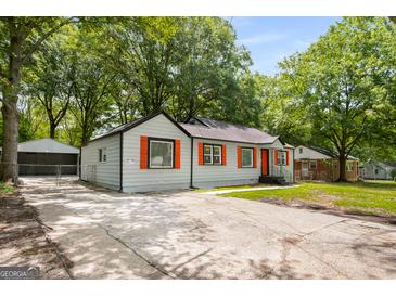Charming single-story home features a concrete driveway, gray siding, and vibrant orange window shutters at 5180 Ash St, Forest Park, GA 30297