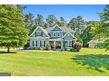 Charming two-story home featuring a well-manicured lawn, lush landscaping, and inviting front porch at 130 Edgewater Trl, Fayetteville, GA 30215