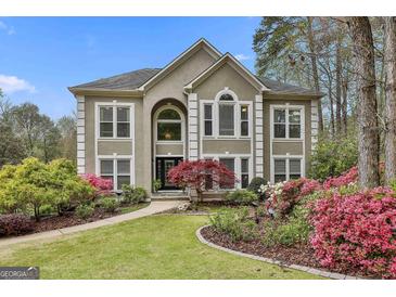 Stucco home featuring professionally landscaped yard with mature trees, colorful azaleas and manicured lawn at 1000 Pleasance Grv, Peachtree City, GA 30269