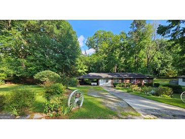 Charming single-story brick home with mature trees and a long driveway at 4884 Maurice Nw Dr, Lilburn, GA 30047