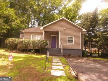 Charming home with a lovely front yard and unique purple front door, surrounded by lush greenery at 2134 Main Nw St, Atlanta, GA 30318