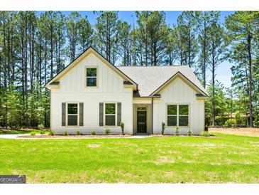 Beautiful home with white siding, black shutters, and a well-manicured lawn surrounded by many trees at 1547 South Bethany Rd, Locust Grove, GA 30248