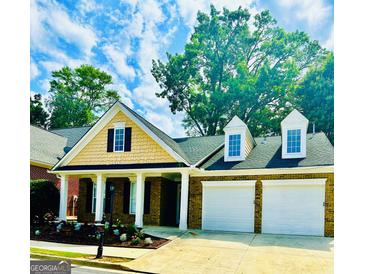 Charming brick home with a two-car garage, manicured lawn, and inviting front porch at 2200 Hickory Station Cir, Snellville, GA 30078