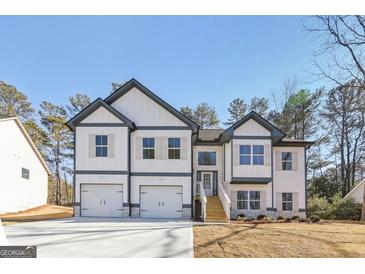 Charming two-story home featuring a two-car garage, stone accents, and a welcoming entrance with wooden steps at 3278 Greenhill Dr, Villa Rica, GA 30180