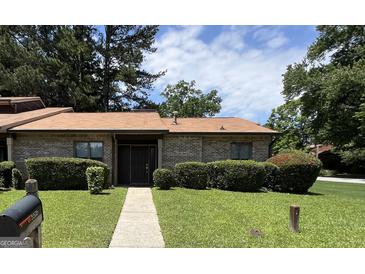 Charming brick home featuring a well-manicured lawn, mature trees, and welcoming front entrance at 5526 Stoneleigh Court, Stone Mountain, GA 30088