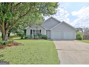 Charming gray home with a two-car garage, lush green lawn, and lovely landscaping at 10690 Tara Village Way, Joneboro, GA 30238