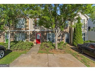 Charming townhome featuring stone accents, colorful door, mature trees and a convenient parking pad at 11439 South Grove Dr, Hampton, GA 30228