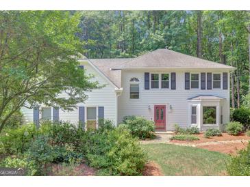 Charming two-story home with a red door and landscaped yard and a lush green tree in the front at 157 Rockspray Rdg, Peachtree City, GA 30269