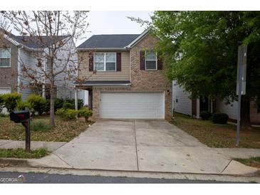 Charming two-story home with a brick and beige exterior, integrated garage, and a concrete driveway at 1579 Leonard St, Hampton, GA 30228
