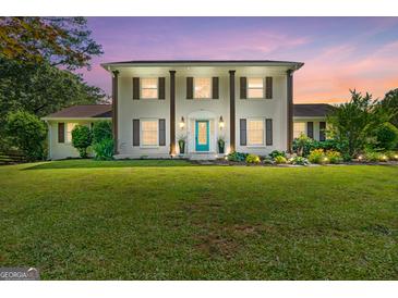Traditional two-story white home with brown shutters, lush landscaping, and a vibrant blue front door at 75 Auburn Rd, Auburn, GA 30011