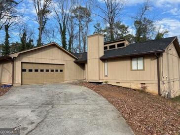 Charming single-story home features attached garage and neutral-toned siding, set in a wooded landscape at 1725 Sara Se Ct, Conyers, GA 30013