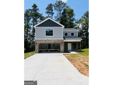 Two story home showing gray siding, brick foundation and large driveway surrounded by mature trees at 8035 Buffet Trl, Riverdale, GA 30296