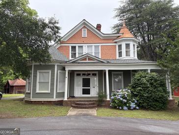 Charming two-story home featuring a quaint covered porch with blooming hydrangeas and unique architectural details at 435 Jackson St, Locust Grove, GA 30248