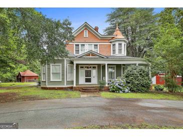 Charming two-story home with a welcoming front porch and a well-manicured lawn and beautiful accent turrets at 435 Jackson St, Locust Grove, GA 30248