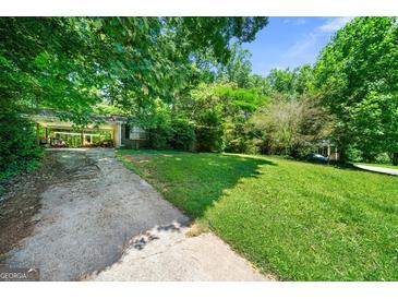 Exterior view of a home with a covered driveway and spacious front yard, offering lots of green space at 2257 Chestnut Log Loop, Lithia Springs, GA 30122