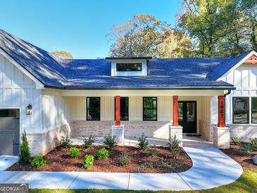 Beautiful front exterior with a walkway, manicured landscaping, and a covered porch with red accents and neutral brickwork at 1947 Clark Dr, Tucker, GA 30084