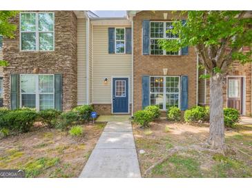 Charming townhome featuring stone and brick accents, a walkway, and lush landscaping at 1851 Grove Way, Hampton, GA 30228