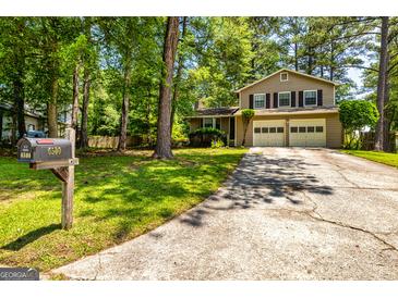 Charming two-story home with a two-car garage and long driveway, surrounded by lush greenery and mature trees at 6500 Wild Turkey Trl, Riverdale, GA 30296