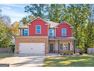 Inviting two-story home featuring a brick and red-sided facade, an attached two-car garage, and a well-manicured lawn at 475 Louise Way, Locust Grove, GA 30248