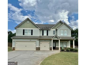 Two-story home with light-blue siding, black shutters, three-car garage, and well-maintained landscaping at 9108 Alden Dr, Locust Grove, GA 30248