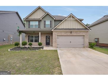 Charming two-story home features a brick facade, two-car garage, and well-manicured lawn at 9046 Holder Rd, Locust Grove, GA 30248