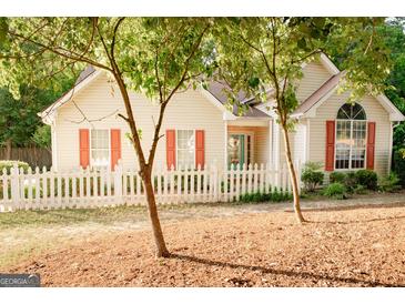 Charming home featuring a white picket fence, complemented by trees and light-colored siding with red shutters at 110 Orchard Vw, Fayetteville, GA 30215