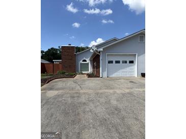 Home exterior with a brick chimney, one car garage and a concrete driveway on a sunny day at 135 Courtyard Ln, Fayetteville, GA 30215