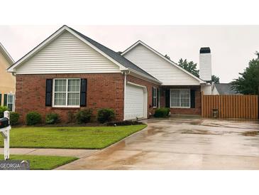 Charming brick home with well-maintained lawn, attached garage and black shutters at 165 Woodgate Cir, Fayetteville, GA 30214