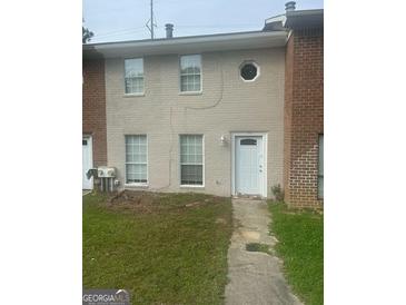 Townhouse exterior featuring a painted brick facade, white door and windows, and a small front yard at 1321 Lakeview Nw Dr, Conyers, GA 30012
