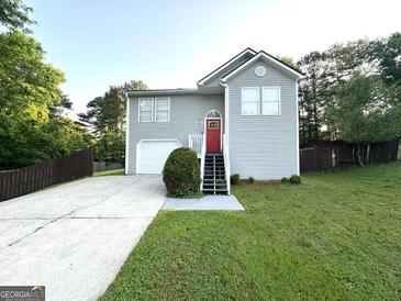 Charming home with gray siding, a red front door, a driveway, and a fenced yard at 3170 W Point Cir, Douglasville, GA 30135