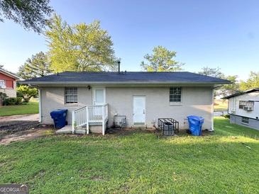 Exterior shot of a white brick home with an enclosed backyard and a well-maintained lawn at 4039 Codel Nw St, Atlanta, GA 30331