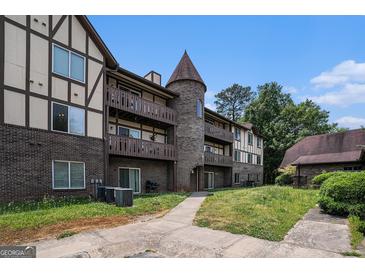 Three-story apartment building with brick and siding exterior, multiple balconies, and unique turret design at 1017 Camelot Dr, Atlanta, GA 30349