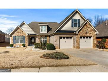 Charming home featuring a three-car garage, brick accents, manicured landscaping, and well-maintained lawn at 409 Brandy Ln, Mcdonough, GA 30253